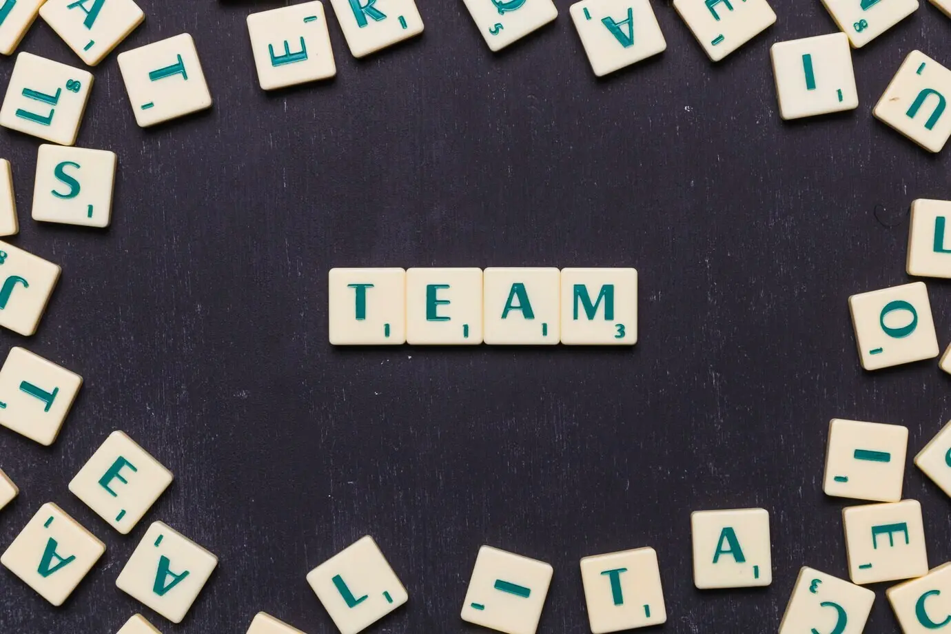 Das Wort Team aus Scrabble-Steinen vor schwarzem Hintergrund.